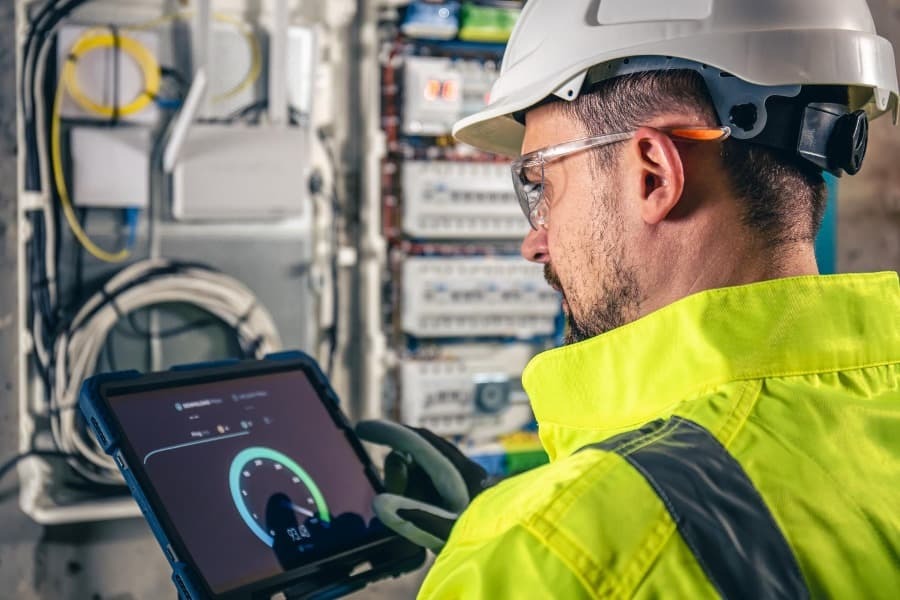 Homem vestido com EPIs medindo a tensão da caixa de energia Homem vestido com EPIs medindo a tensão da caixa de energia